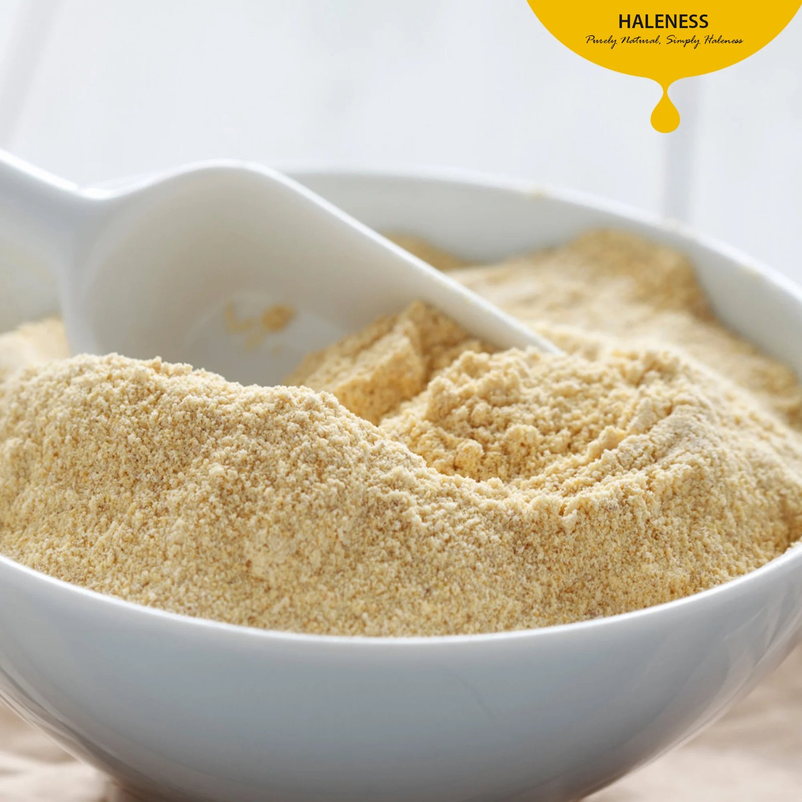 A white bowl filled with a light-brown, finely-milled banana powder, with a large white scoop resting inside.